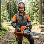 Forester holding a modern 2-stroke chainsaw in a forest